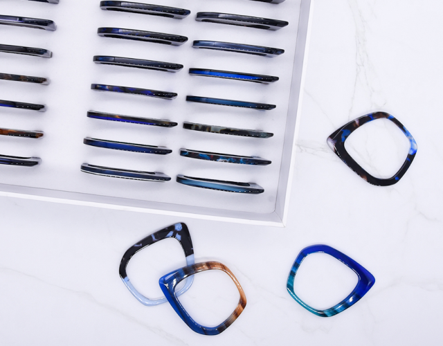Frames: A selection of finished eco eyeglass frames and frame parts in different shapes and colors, demonstrating the final glasses frames made from the biodegradable cellulose acetate material.